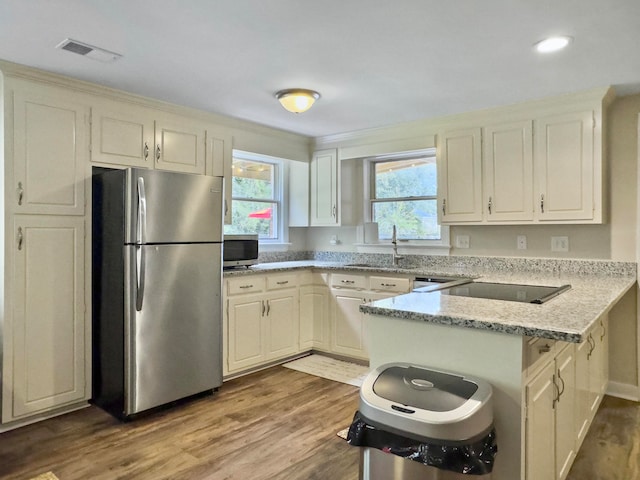 kitchen featuring kitchen peninsula, sink, light wood-type flooring, light stone countertops, and stainless steel appliances