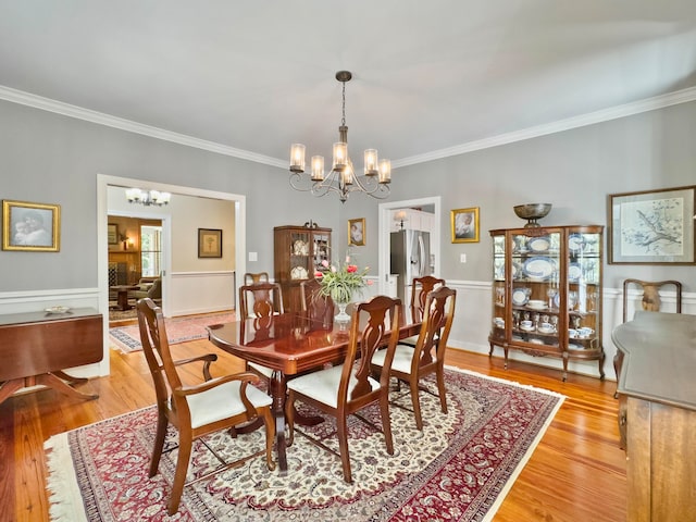 dining room with an inviting chandelier, crown molding, and light hardwood / wood-style floors