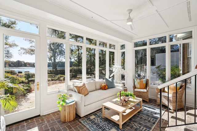 sunroom / solarium with ceiling fan and a water view