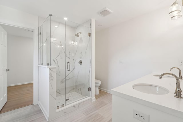 bathroom with vanity, hardwood / wood-style floors, a shower with shower door, and toilet