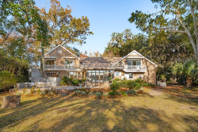 rear view of house with a balcony, a yard, and a patio area