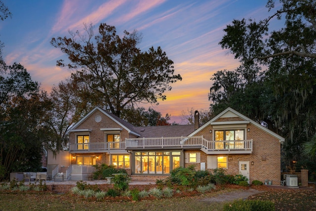 back house at dusk featuring a balcony and central AC