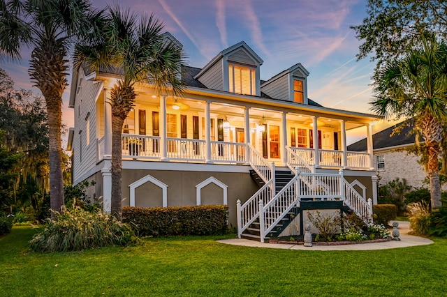 back house at dusk with a porch and a yard