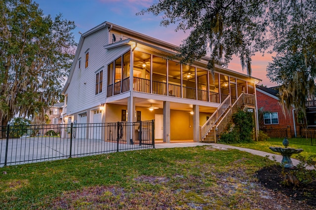 back house at dusk with a patio area, a sunroom, a yard, and a garage