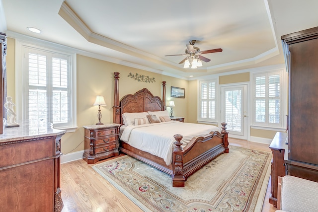 bedroom featuring light wood-type flooring, ornamental molding, access to outside, a raised ceiling, and ceiling fan