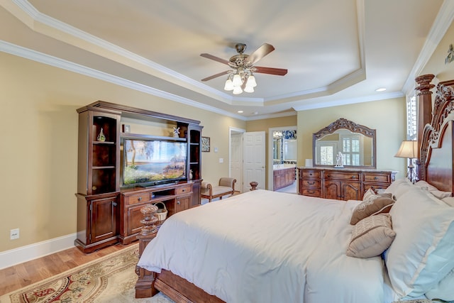 bedroom with connected bathroom, ceiling fan, light hardwood / wood-style flooring, a tray ceiling, and ornamental molding