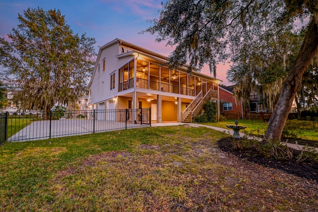 back house at dusk with a yard, a garage, and a sunroom