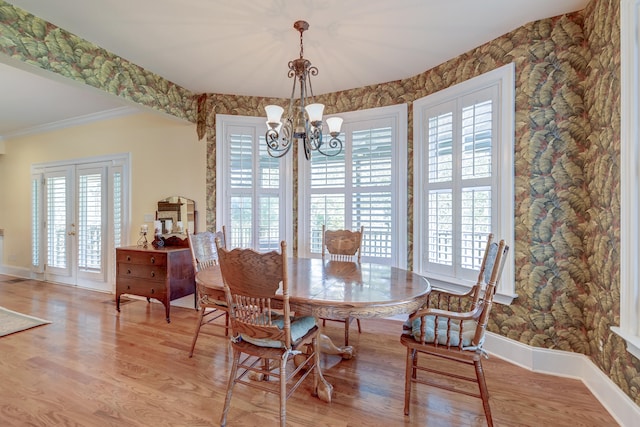 dining room featuring french doors, an inviting chandelier, light hardwood / wood-style flooring, and ornamental molding