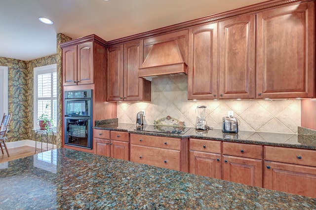 kitchen with black appliances, dark stone countertops, custom range hood, and tasteful backsplash