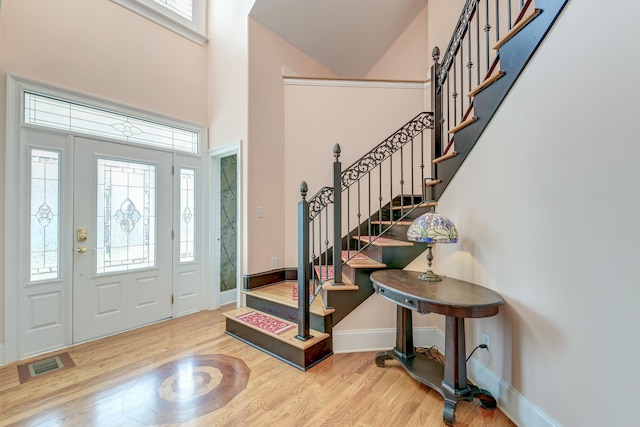 foyer with a towering ceiling and light hardwood / wood-style floors