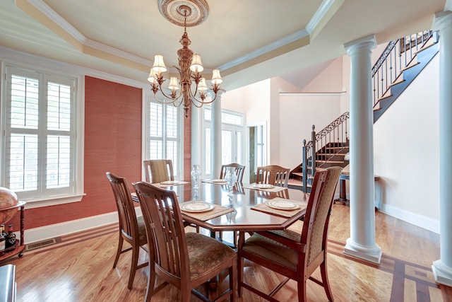 dining room featuring a tray ceiling, a wealth of natural light, and light hardwood / wood-style flooring