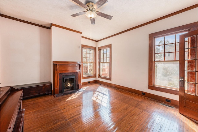 unfurnished living room with wood-type flooring, crown molding, a textured ceiling, and baseboards