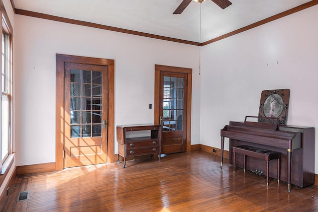 interior space with baseboards, visible vents, ceiling fan, ornamental molding, and hardwood / wood-style floors