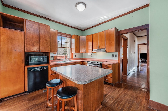 kitchen featuring brown cabinets, dark wood finished floors, under cabinet range hood, and black appliances