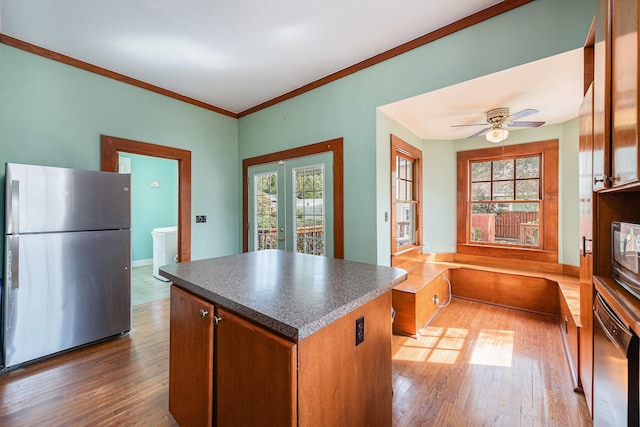 kitchen with dark countertops, appliances with stainless steel finishes, hardwood / wood-style floors, and a center island