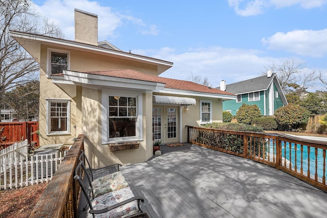 wooden terrace featuring fence, a fenced in pool, and french doors