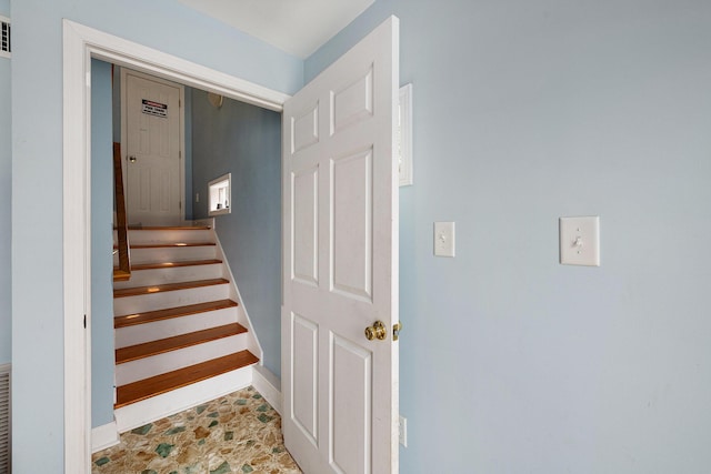 stairway with stone finish floor and baseboards