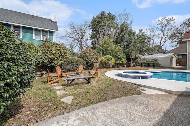 view of swimming pool featuring a patio, a storage shed, fence, an outdoor structure, and a fire pit