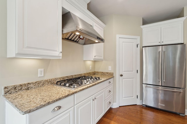 kitchen featuring appliances with stainless steel finishes, white cabinets, dark wood finished floors, and wall chimney range hood