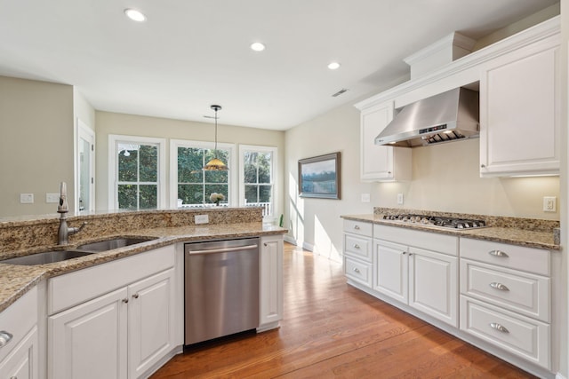 kitchen with light wood-style flooring, a sink, gas stovetop, dishwasher, and wall chimney exhaust hood