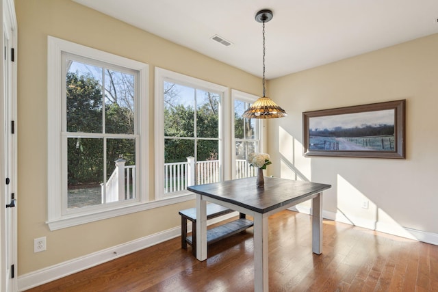 dining space with dark wood-type flooring, visible vents, and baseboards