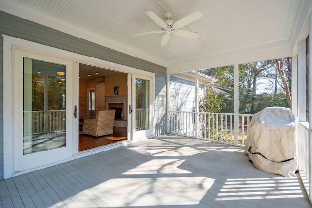 sunroom / solarium featuring ceiling fan and an outdoor fireplace