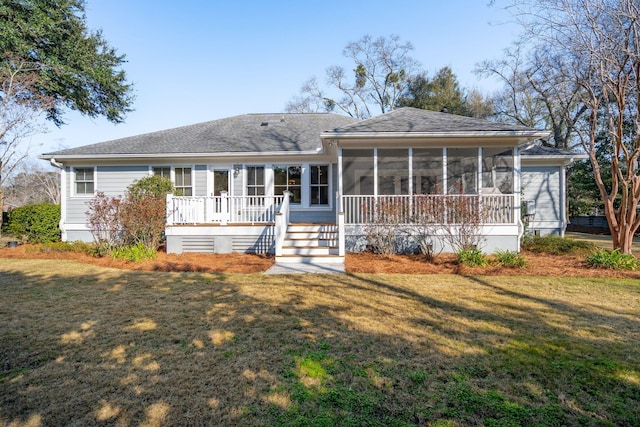 rear view of house featuring a sunroom and a lawn