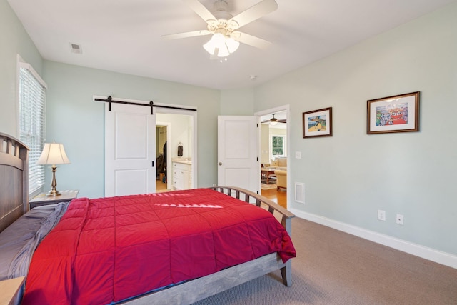 bedroom with carpet, visible vents, a barn door, connected bathroom, and baseboards