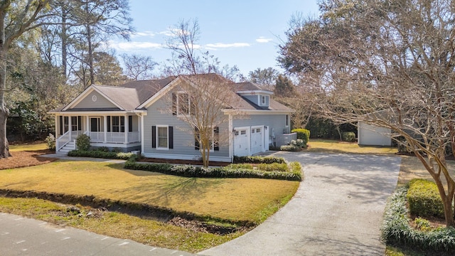 view of front facade with driveway, an attached garage, a porch, and a front yard