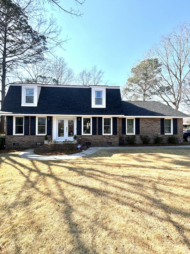 view of property featuring roof with shingles, a front lawn, crawl space, and brick siding