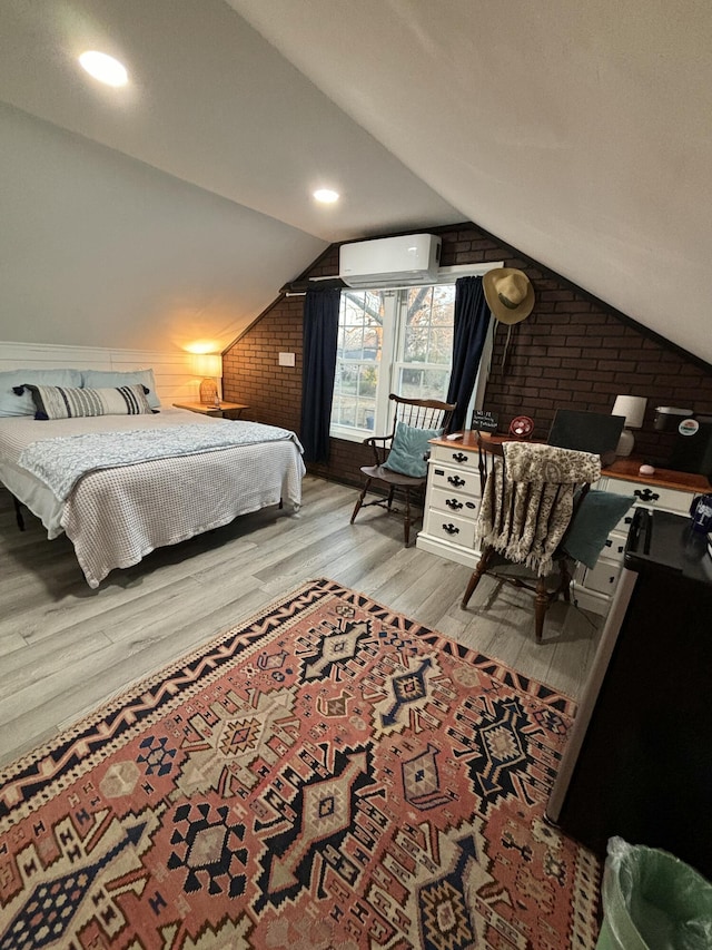 bedroom featuring lofted ceiling, brick wall, wood finished floors, and a wall mounted air conditioner