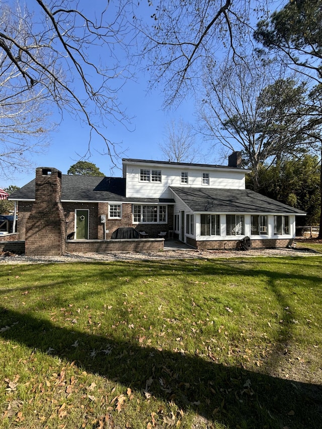 back of property featuring a patio area, a lawn, a chimney, and brick siding