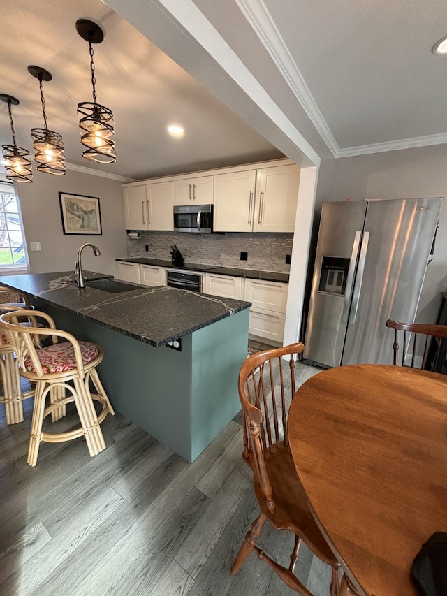 kitchen featuring stainless steel appliances, a sink, white cabinets, dark wood-style floors, and crown molding