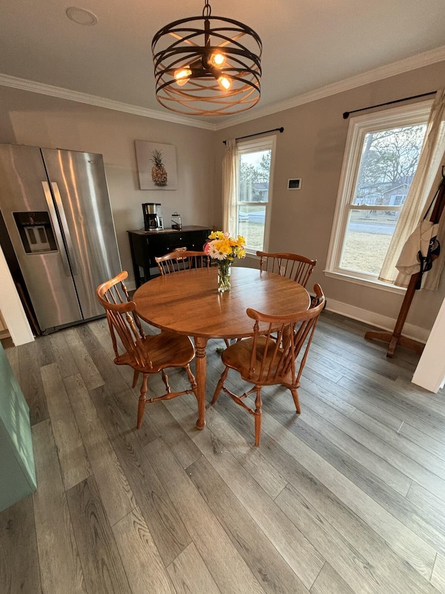 dining space with a notable chandelier, baseboards, ornamental molding, and wood finished floors