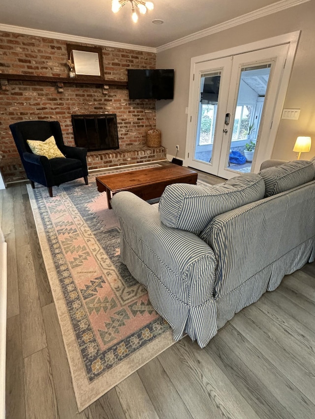 living room with brick wall, a fireplace, wood finished floors, french doors, and crown molding