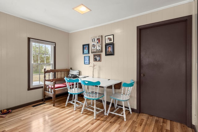 dining space with crown molding and light hardwood / wood-style floors