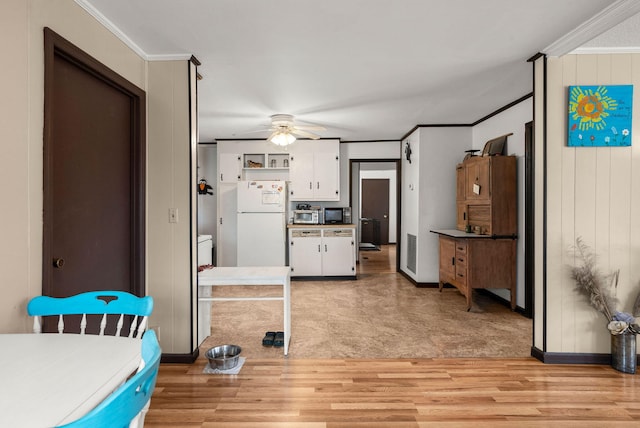 kitchen featuring white cabinetry, crown molding, light wood-type flooring, white fridge, and ceiling fan