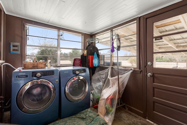 clothes washing area with washer and dryer and wood walls