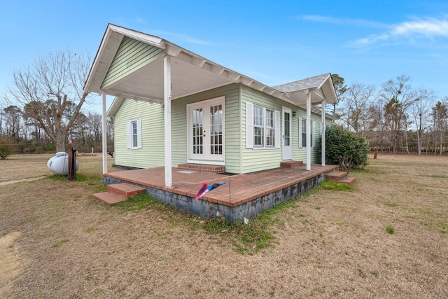 view of side of home featuring a lawn, french doors, and a deck