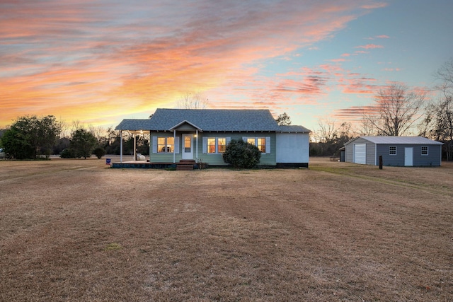 view of front facade featuring a garage, a porch, an outbuilding, and a yard