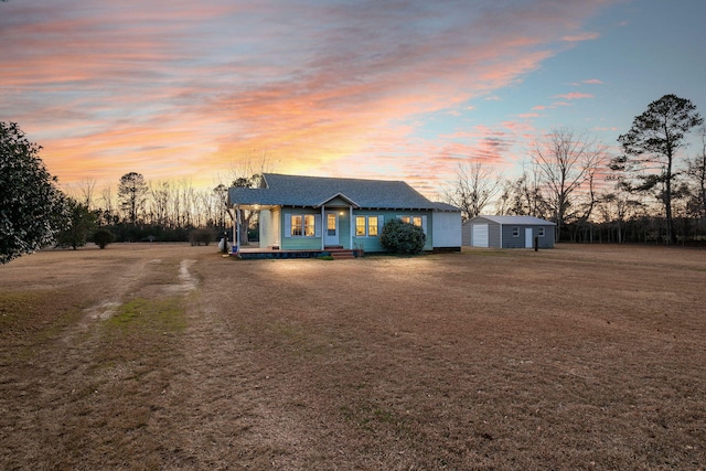 single story home featuring a shed, covered porch, and a lawn