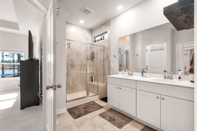 bathroom featuring double vanity, a sink, visible vents, and a shower stall