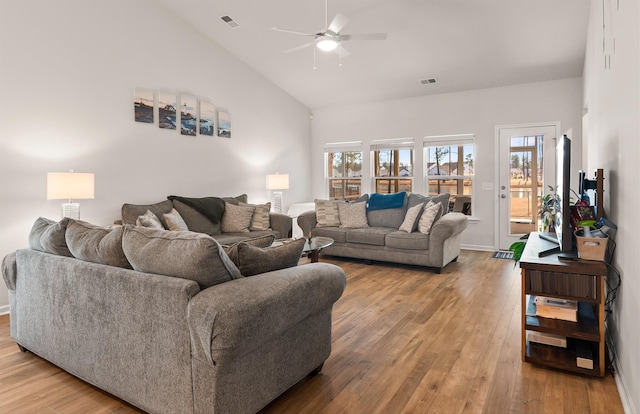 living room with high vaulted ceiling, a ceiling fan, visible vents, and light wood-style floors