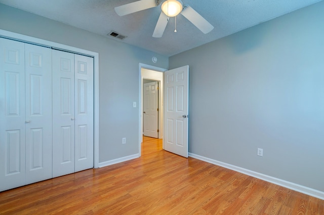 unfurnished bedroom with a closet, light hardwood / wood-style floors, a textured ceiling, and ceiling fan