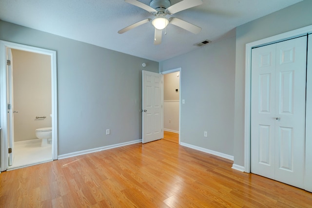 unfurnished bedroom with light wood-type flooring, ceiling fan, a closet, and connected bathroom