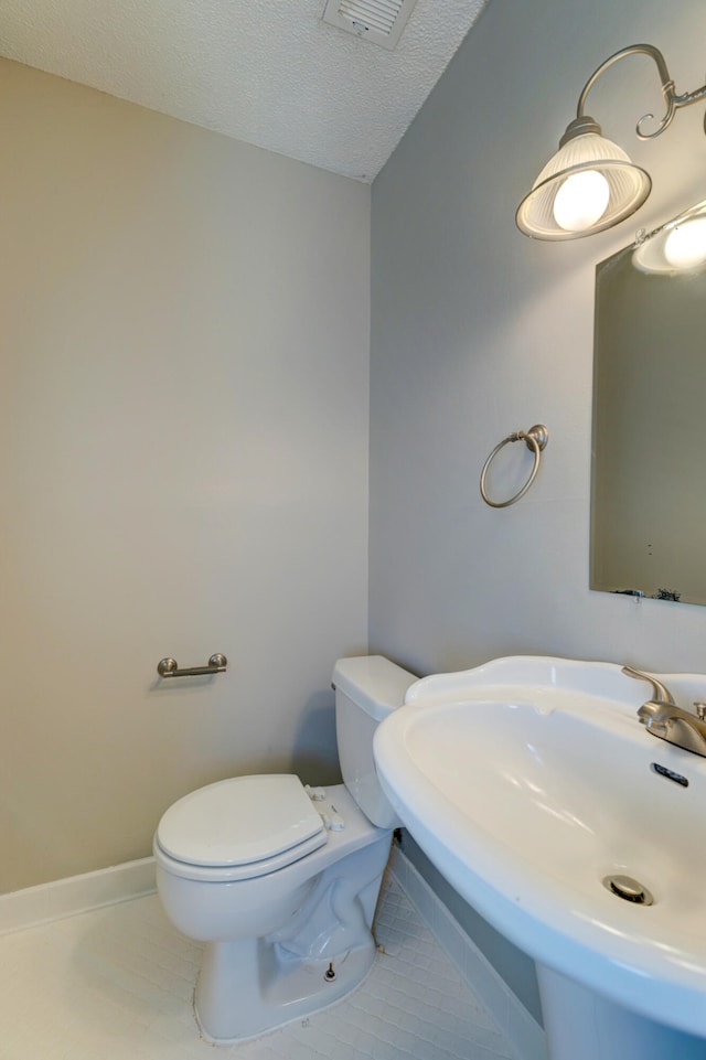 bathroom with tile patterned floors, a textured ceiling, sink, and toilet