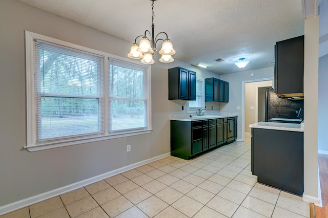 kitchen featuring sink, light tile patterned floors, decorative light fixtures, a chandelier, and fridge