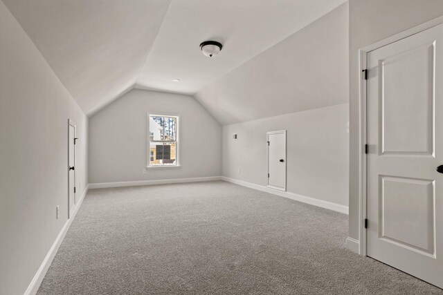 bonus room with lofted ceiling and light carpet