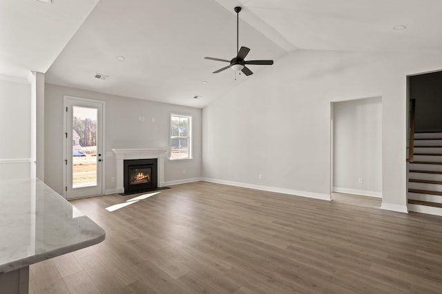 unfurnished living room with dark wood-type flooring, ceiling fan, and vaulted ceiling