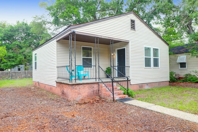 view of front facade featuring covered porch, crawl space, and fence